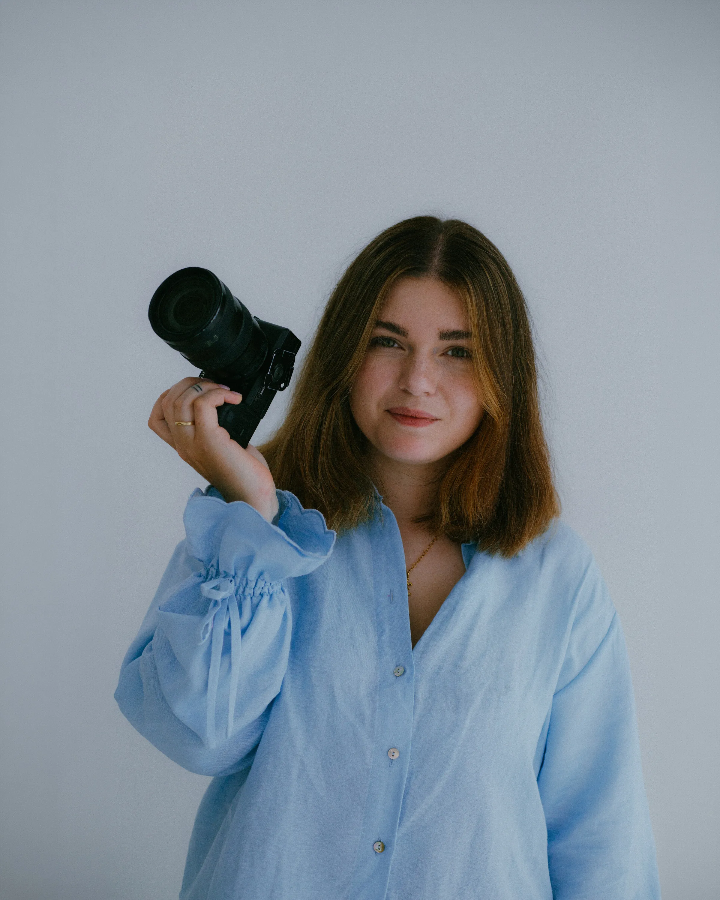 Angelika Pankowska, fotografka ciążowa, noworodkowa i rodzinna z Warszawy, z aparatem w dłoni.